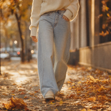 Weite helle Jeans auf einem Gehweg mit Herbstlaub
