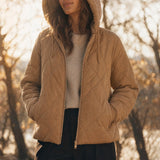 Frau in beiger Steppjacke mit Kapuze im Herbstlicht