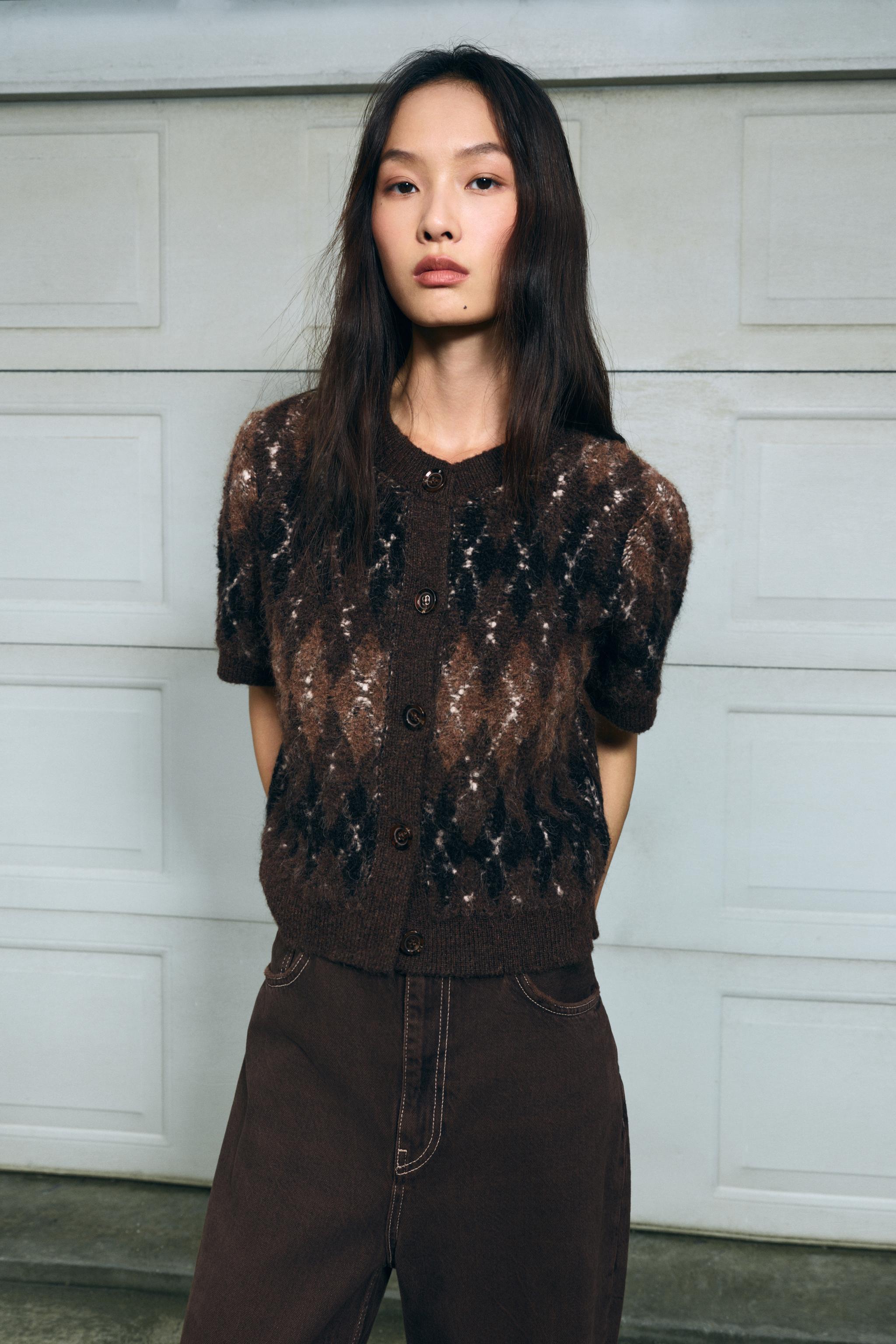 frau trägt kurze braune strickjacke mit argyle-muster und knöpfen in der stadt