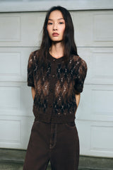 frau trägt kurze braune strickjacke mit argyle-muster und knöpfen in der stadt