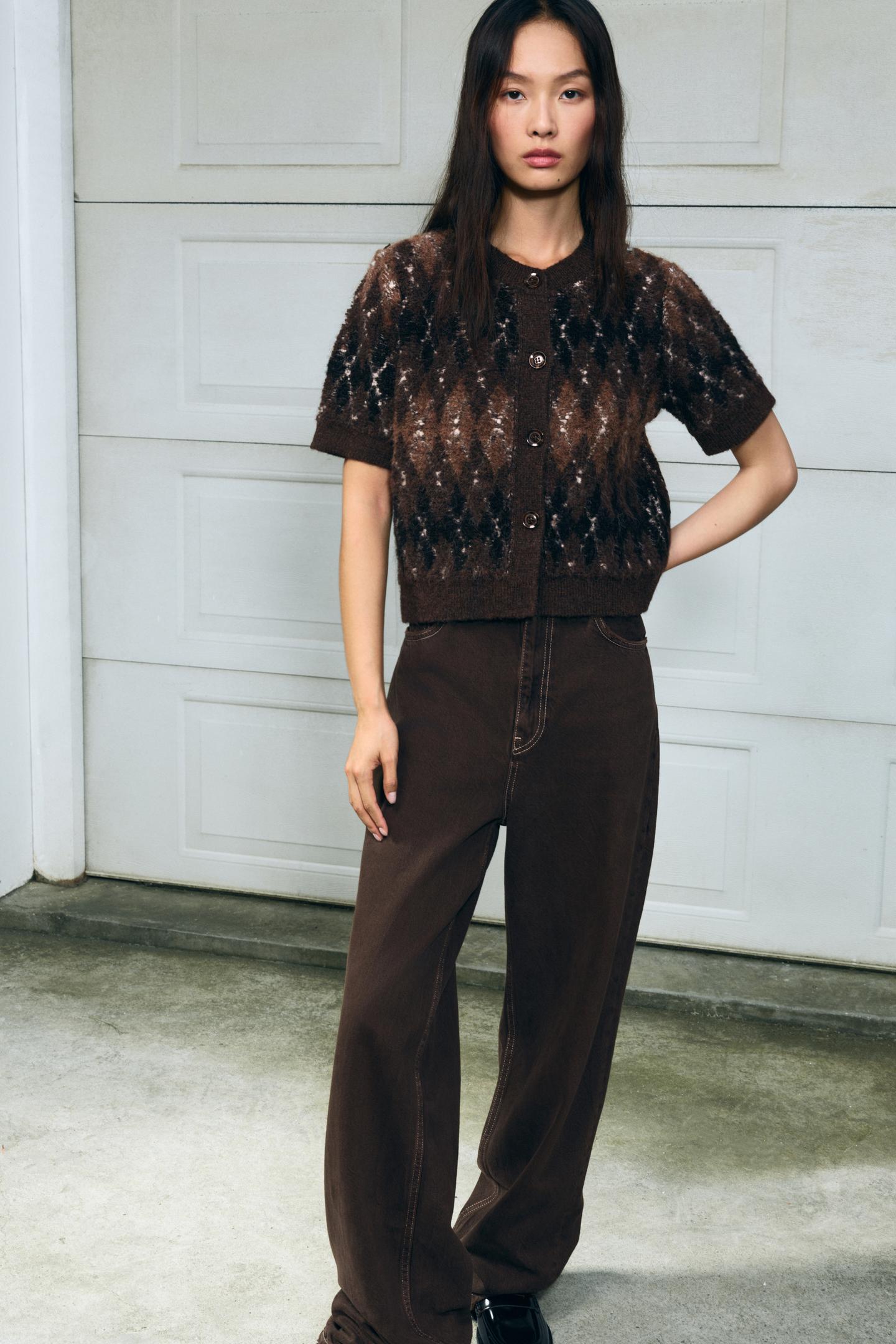 frau trägt kurze braune strickjacke mit argyle-muster und knöpfen in der stadt