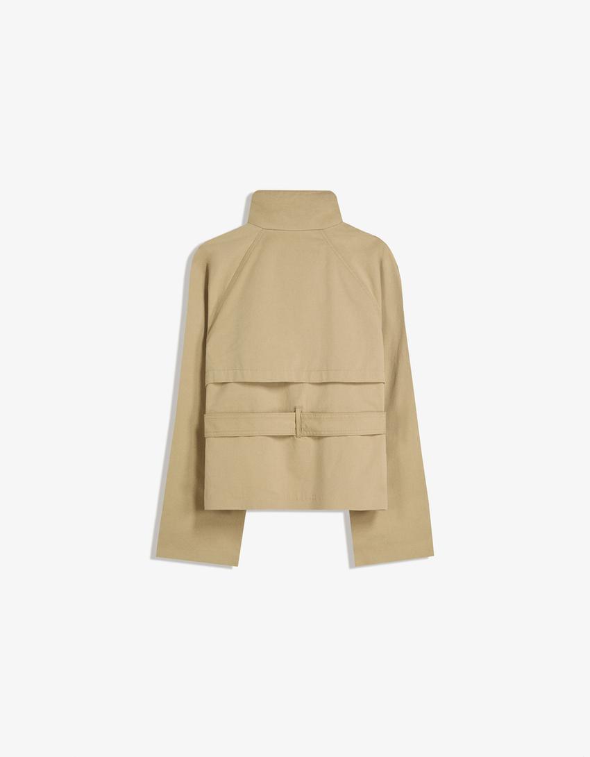 beige kurzer trenchcoat flach fotografiert mit hohem stehkragen