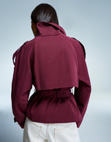 frau trägt bordeaux kurzen trenchcoat mit hohem kragen und gürtel