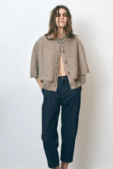 model trägt taupe strickweste mit cape-look und knöpfen, kombiniert mit jeans