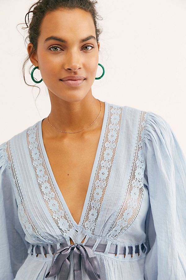 Modell trägt Lunaria Bluse in Hellblau – Detailaufnahme der Spitzen-Front und Schleife