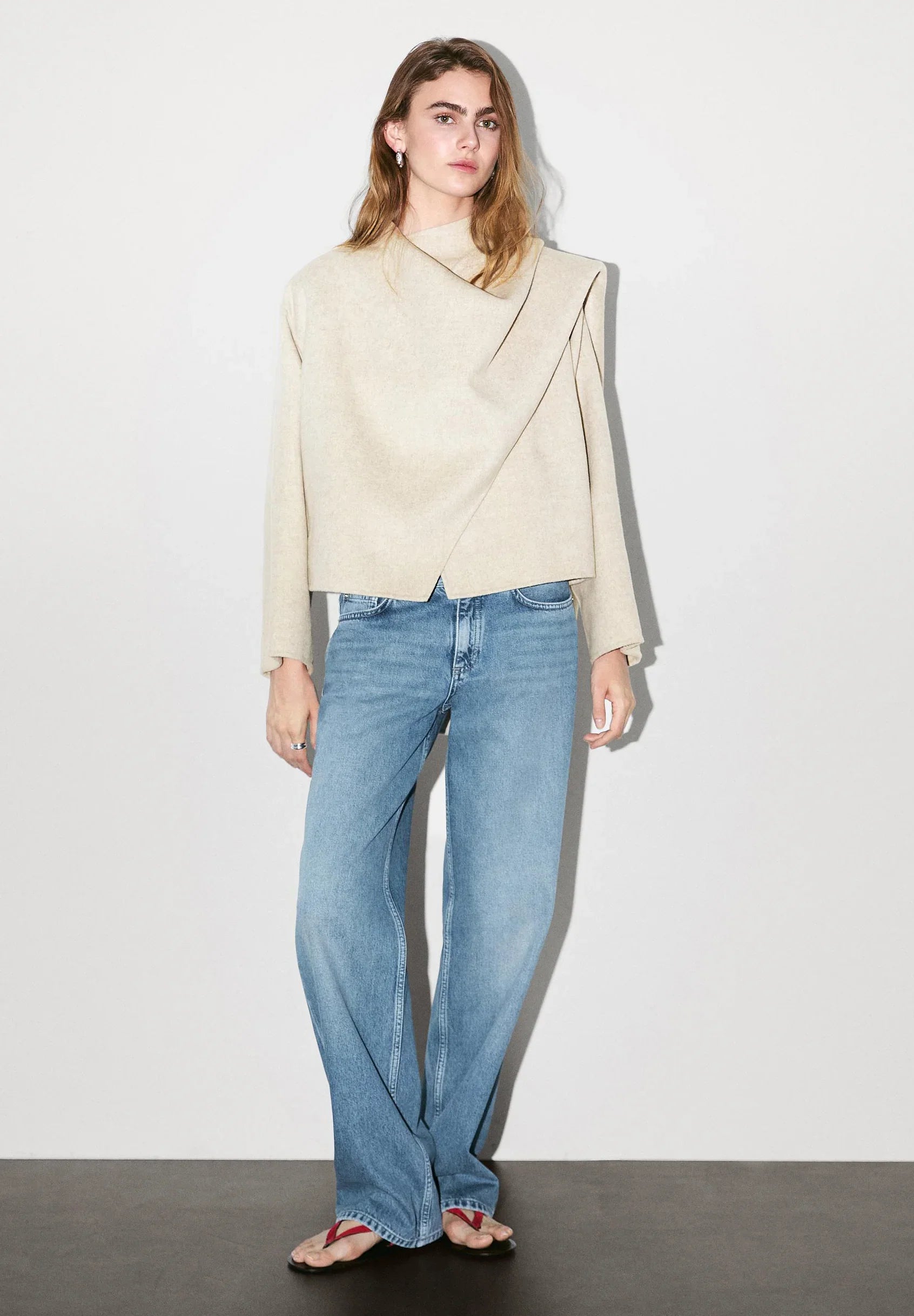 Model trägt beigen asymmetrischen Wollmantel mit Schal-Detail