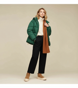 frau mit grüner daunenjacke, weißem rollkragenpullover und braunen winter boots