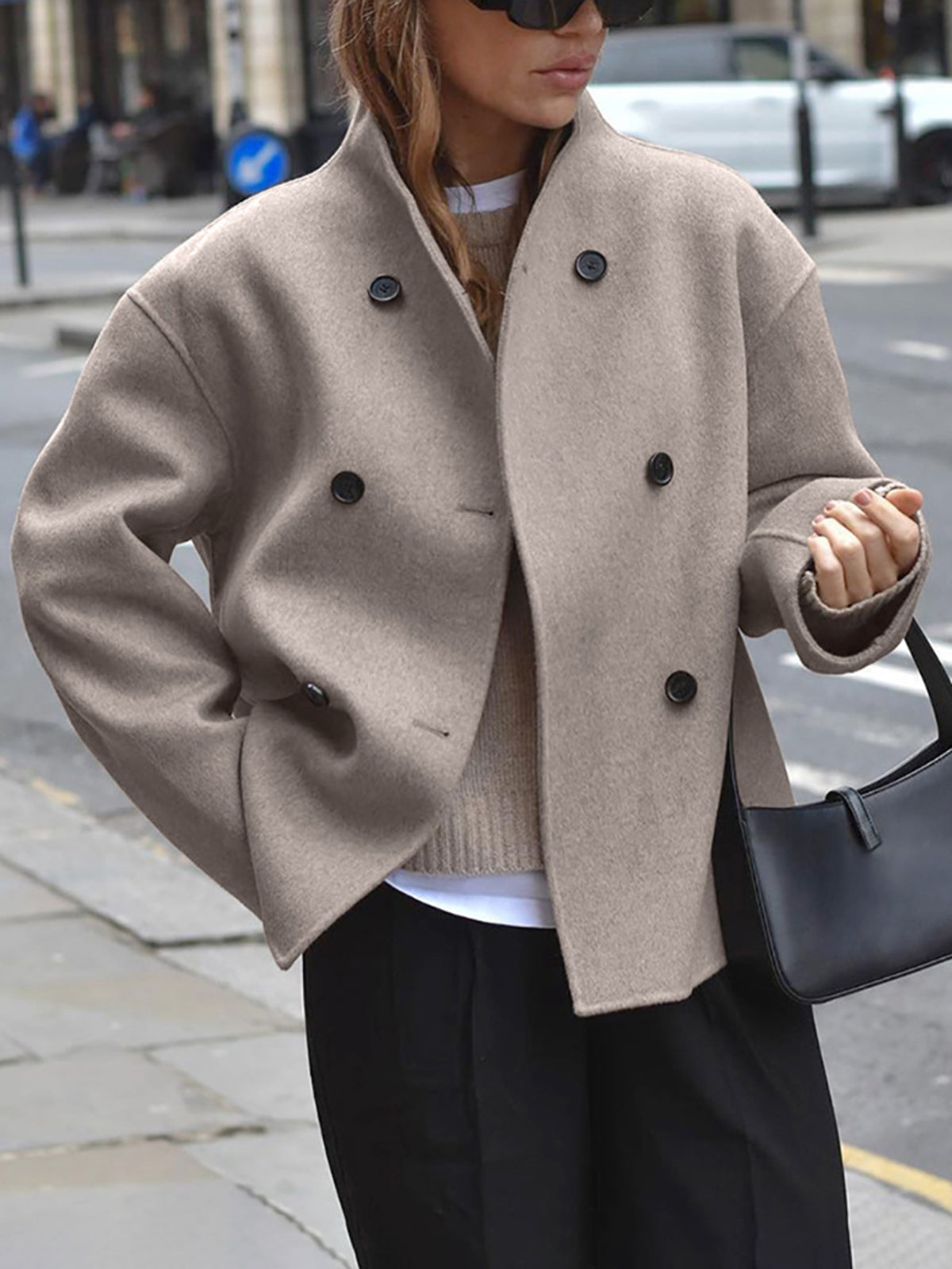 Model draagt oversized jas in beige op straat
