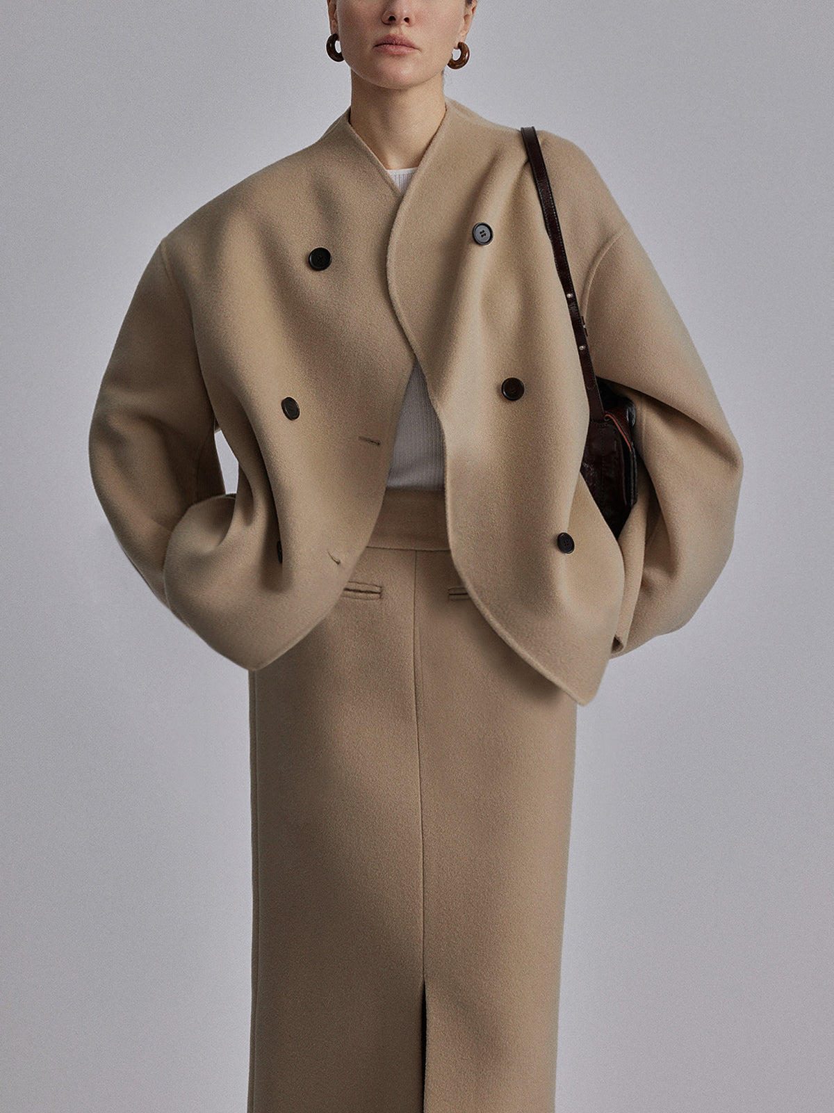 Model in beige jas met dubbele knopen en bijpassende rok

