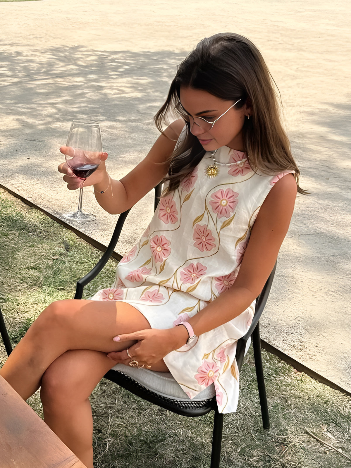 Model zittend met glas wijn in zomerse bloemenjurk

