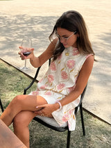 Model zittend met glas wijn in zomerse bloemenjurk
