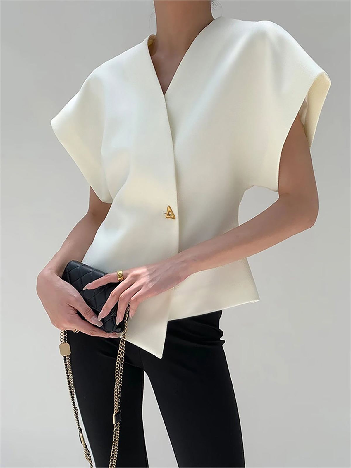 Model draagt witte Velina blouse met gouden knoop
