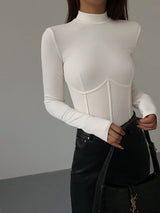 Model draagt witte Meliora top met piping en mock neck
