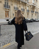 Achteraanzicht model met Vesper Luxe Coat zwart, gestyled met zwarte tas
