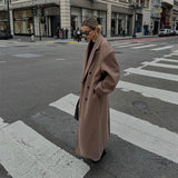Vesper Luxe Coat in bruin gedragen over casual outfit met sneakers
