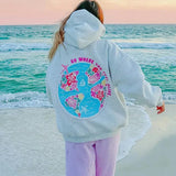 Grauer Hoodie mit bunter Weltkarten-Rückseite am Strand
