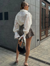 Model draagt een elegante witte blouse gecombineerd met een panterprint rok