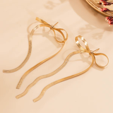 Paar Liora Bow Ohrringe in Gold und Silber auf Stoff
