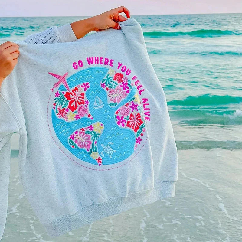 Grauer Hoodie mit Travel-Quote „Go where you feel alive“ Vorderseite
