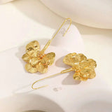 Paar goldene Blumen-Ohrringe auf hellem Hintergrund
