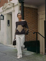 frau kombiniert off-shoulder strickpullover mit weißer hose und handtasche