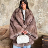 frau trägt hellbraune kunstpelzjacke mit weißer handtasche und jeans