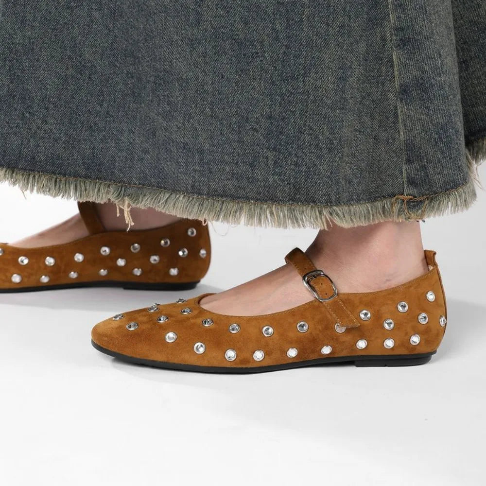 vrouw draagt bruine suède flats met rivets onder een denim rok
