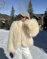 nahaufnahme einer fluffigen beigen kunstpelzjacke mit lockiger struktur