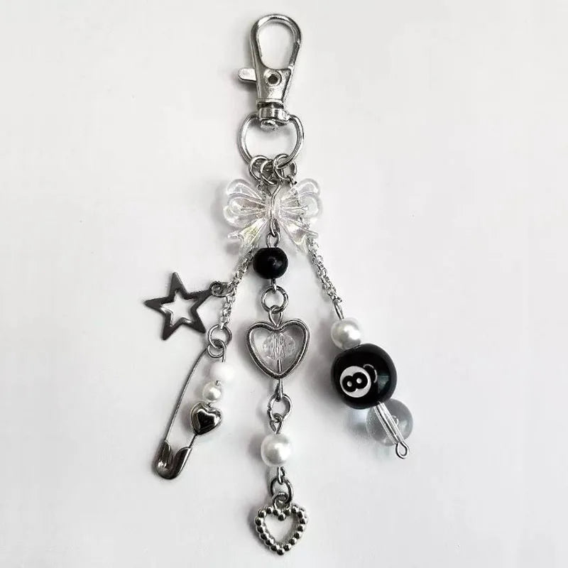 LuckyCharm sleutelhanger met zwarte en witte bedels, hartjes, parels, ster en 8-ball detail – speels accessoire voor tas of sleutelbos