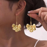 Amarisse Bloom goldene Blumen-Ohrringe am Ohr getragen
