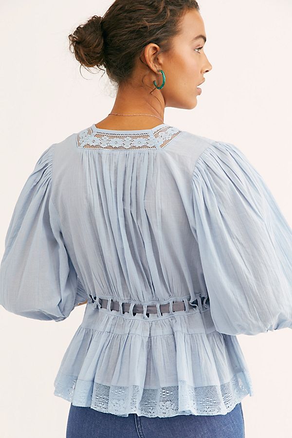 Modell in Lunaria Bluse Hellblau – Rückansicht mit Spitzen-Detail und Plissee-Falten