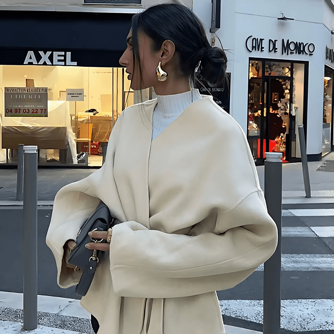 Dalara Mantel in Beige, Seitenansicht abends in der Stadt
