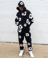 zwarte unisex trainingspak met witte bloemenprint op hoodie en broek
