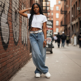 Modell trägt Nyvra Baggy Jeans in Blau und Crop-Top, Streetstyle-Look mit Sneakern