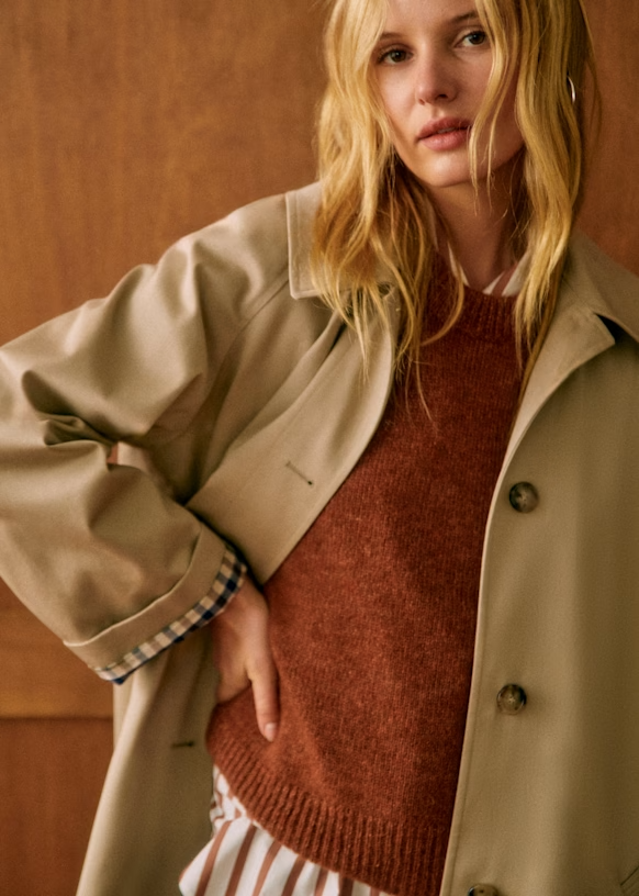 oversized trenchcoat dames, beige trenchcoat met ruitjesvoering, tijdloze trench voor lente en herfst, lange jas dames met knopen, lichte voorjaarsjas met subtiele details, casual chic trenchcoat dames, trendy trench dames met voering, lange jas combineren met jeans, klassieke tussenjas met relaxte fit, gingham voering trenchcoat dames
