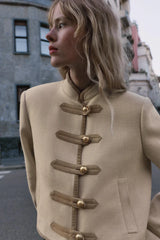 Modell trägt Velmira Taillierte Kurzjacke in Beige mit goldenen Knopf-Riegeln, Streetstyle-Aufnahme